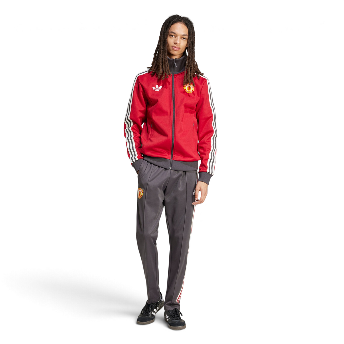 Person wearing a red tracksuit with Adidas and Manchester United logos on a white background