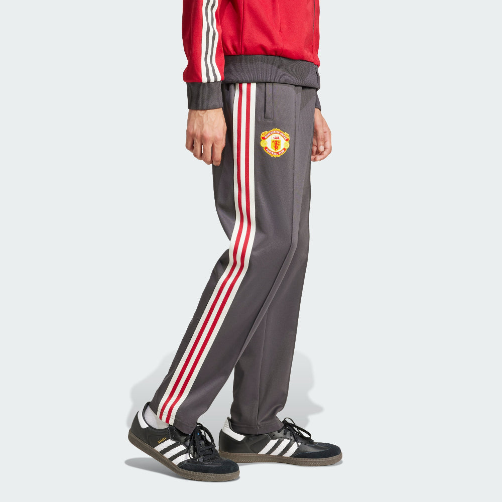 Person wearing gray tracksuit pants with red and white stripes and a visible logo, standing against a light gray background.