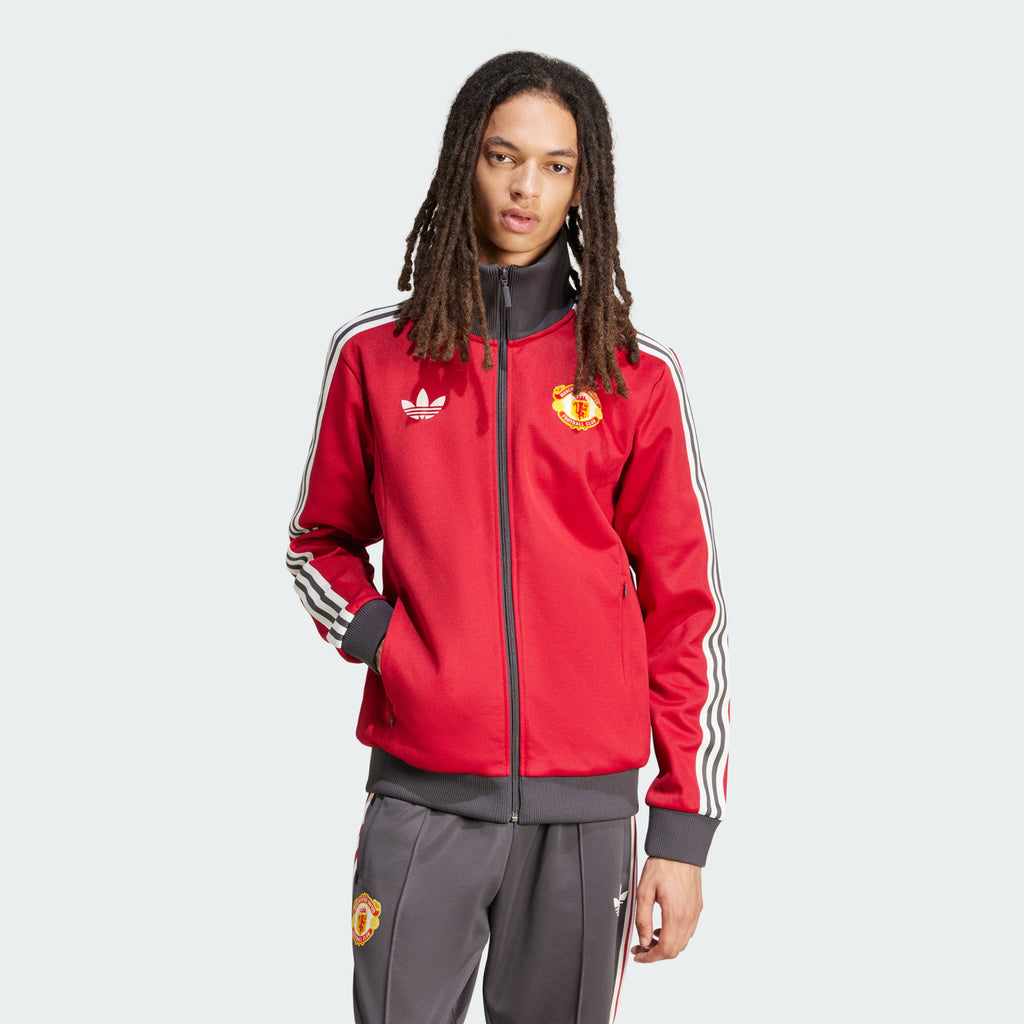 The Team Victory Red track jacket, highlighting the slim-cut sleeves and the iconic white Adidas 3-Stripes running down the arms.