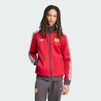 The Team Victory Red track jacket, highlighting the slim-cut sleeves and the iconic white Adidas 3-Stripes running down the arms.