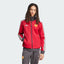 The Team Victory Red track jacket, highlighting the slim-cut sleeves and the iconic white Adidas 3-Stripes running down the arms.