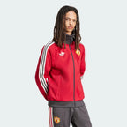 Person wearing a red Adidas tracksuit with white stripes on a light gray background