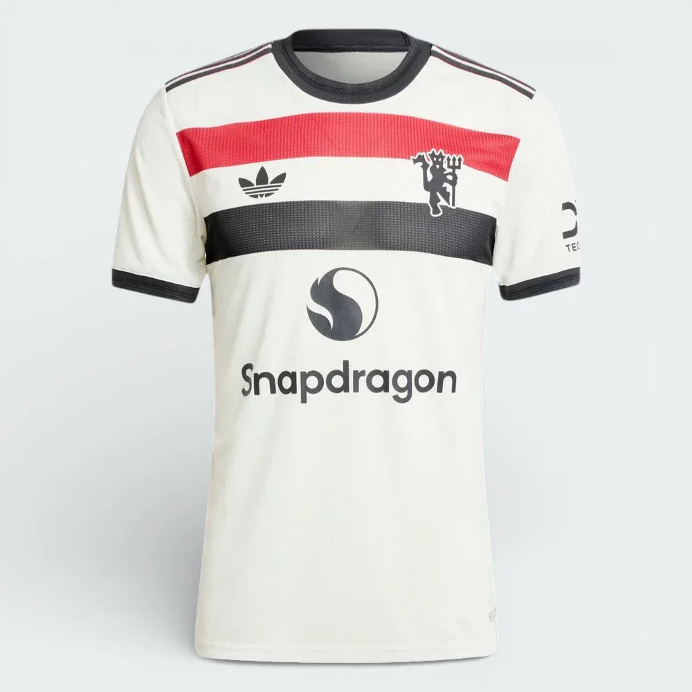 Overhead view of the jersey laid flat, highlighting the tricolour chest bar, the Trefoil logo, and the Red Devil badge.