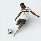Person in sports uniform with visible branding kicking a soccer ball on a white background
