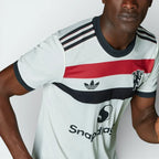 Close-up of the chest area, focusing on the premium heat-applied Trefoil and the iconic Red Devil emblem.