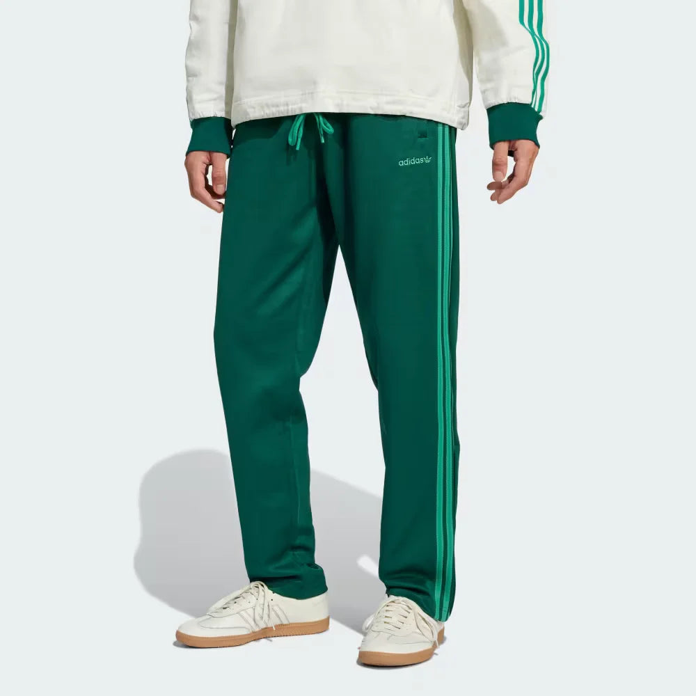 Side profile of the Collegiate Green Heritage pants, highlighting the textured piqué fabric and the crisp white 3-Stripes.