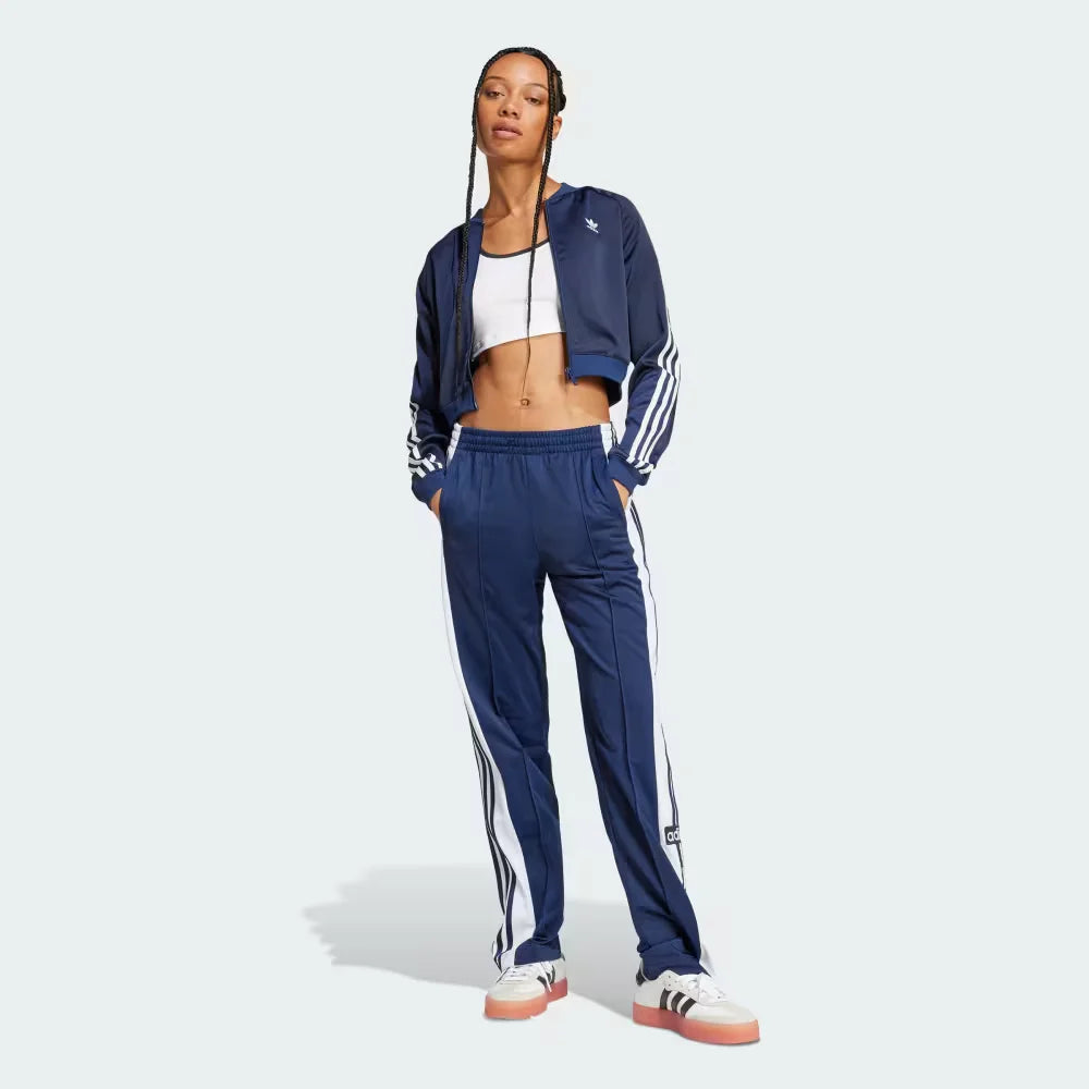 Person wearing a blue tracksuit with white stripes on a light gray background