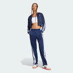 Person wearing a blue tracksuit with white stripes on a light gray background