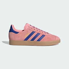 The Semi Pink Spark Gazelle, highlighting the deep Blue 3-Stripes and the slim, low-profile silhouette.