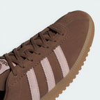 Details the premium dual-stitching lines crossing the velvety brown toe box and the precision lace eyelet layout.