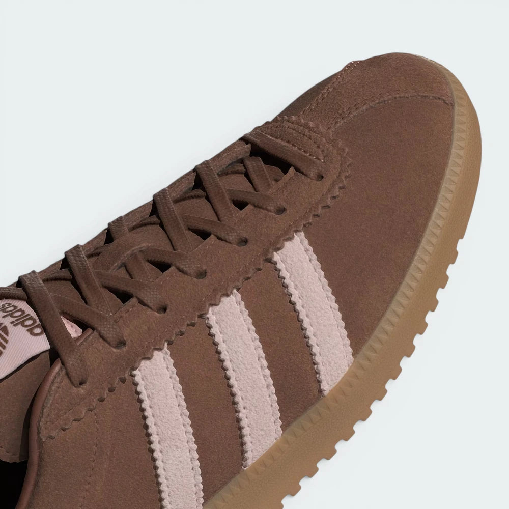 Details the premium dual-stitching lines crossing the velvety brown toe box and the precision lace eyelet layout.