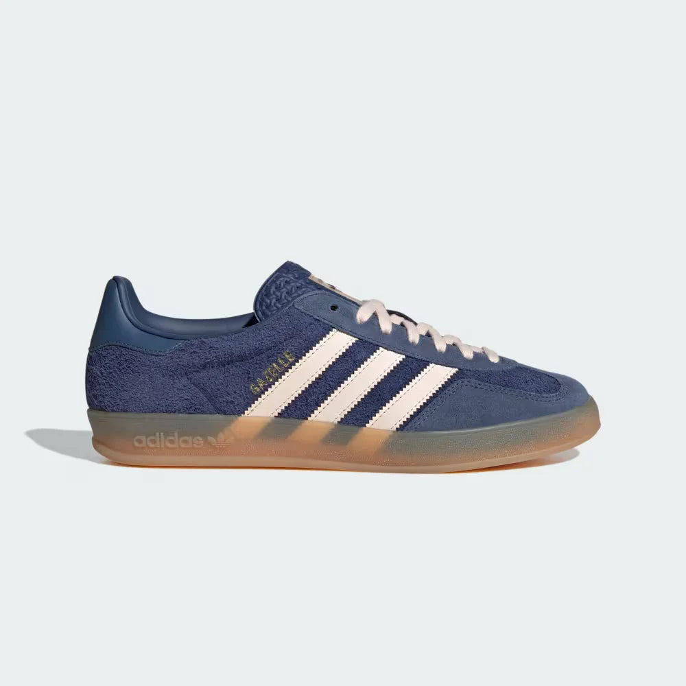 The Dark Blue Gazelle Indoor, highlighting the Bliss Orange 3-Stripes and the iconic translucent gum rubber sole.