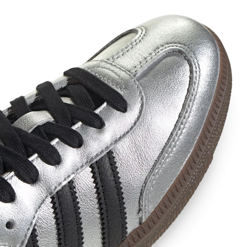 Details the premium stitching lines across the reflective silver T-toe panel and the precision lace eyelet configuration.