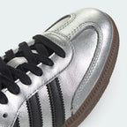Details the premium stitching lines across the reflective silver T-toe panel and the precision lace eyelet configuration.