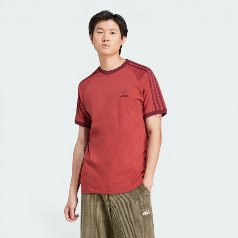 Front profile of the Preloved Ruby Adidas t-shirt, showcasing the iconic white 3-Stripes running from the shoulder to the ribbed cuff. Main image
