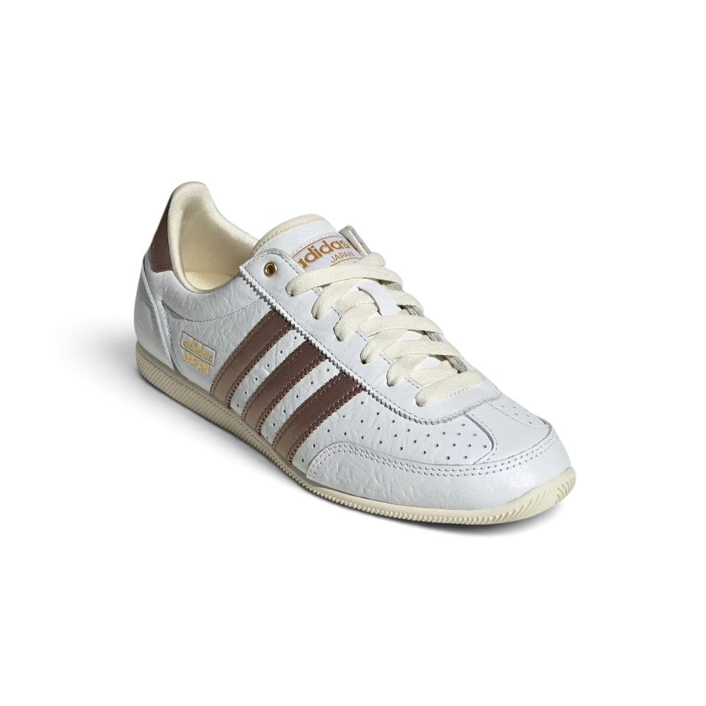 Emphasising the low-slung, athletic silhouette and the clean visual harmony between the Cloud White leather chassis, metallic accents, and brown stripe overlays.