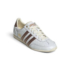 Emphasising the low-slung, athletic silhouette and the clean visual harmony between the Cloud White leather chassis, metallic accents, and brown stripe overlays.