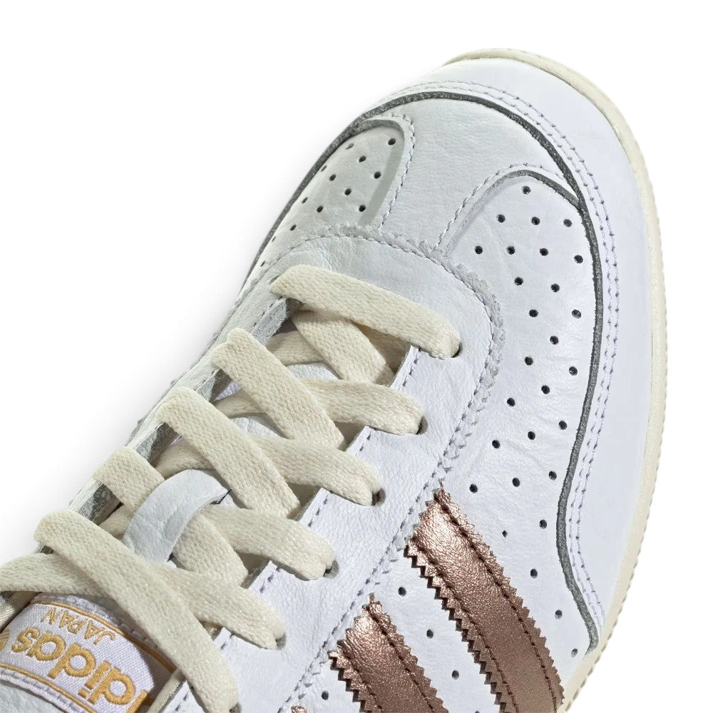Details the micro-precision of the forefoot area, showing the smooth Cloud White leather, double-stitched toe overlay, metallic lace eyelet accents, and crisp laces.