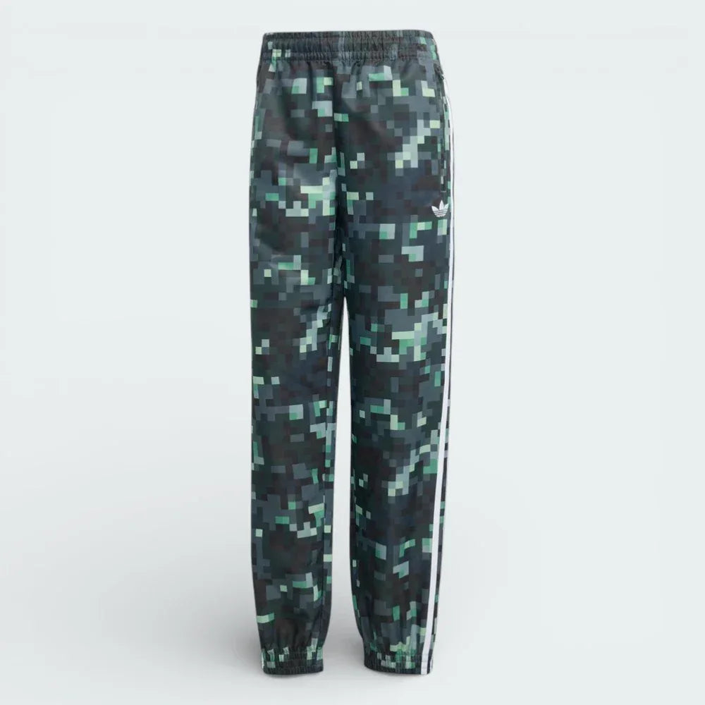 Forward profile of the adidas x Minecraft track pants, showing the colour gradient from light grey to dark green and the woven twill texture.