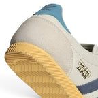 Highlights the "unreal" clean finish where the low-profile rubber sole meets the finely stitched off-white leather upper boundary.
