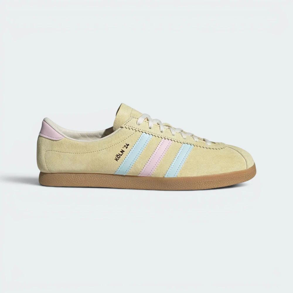 Highlights the high-velocity sweep of the tricolour blue and clear pink 3-Stripes and the professional depth of the gold foil Köln 24 lettering. Main image
