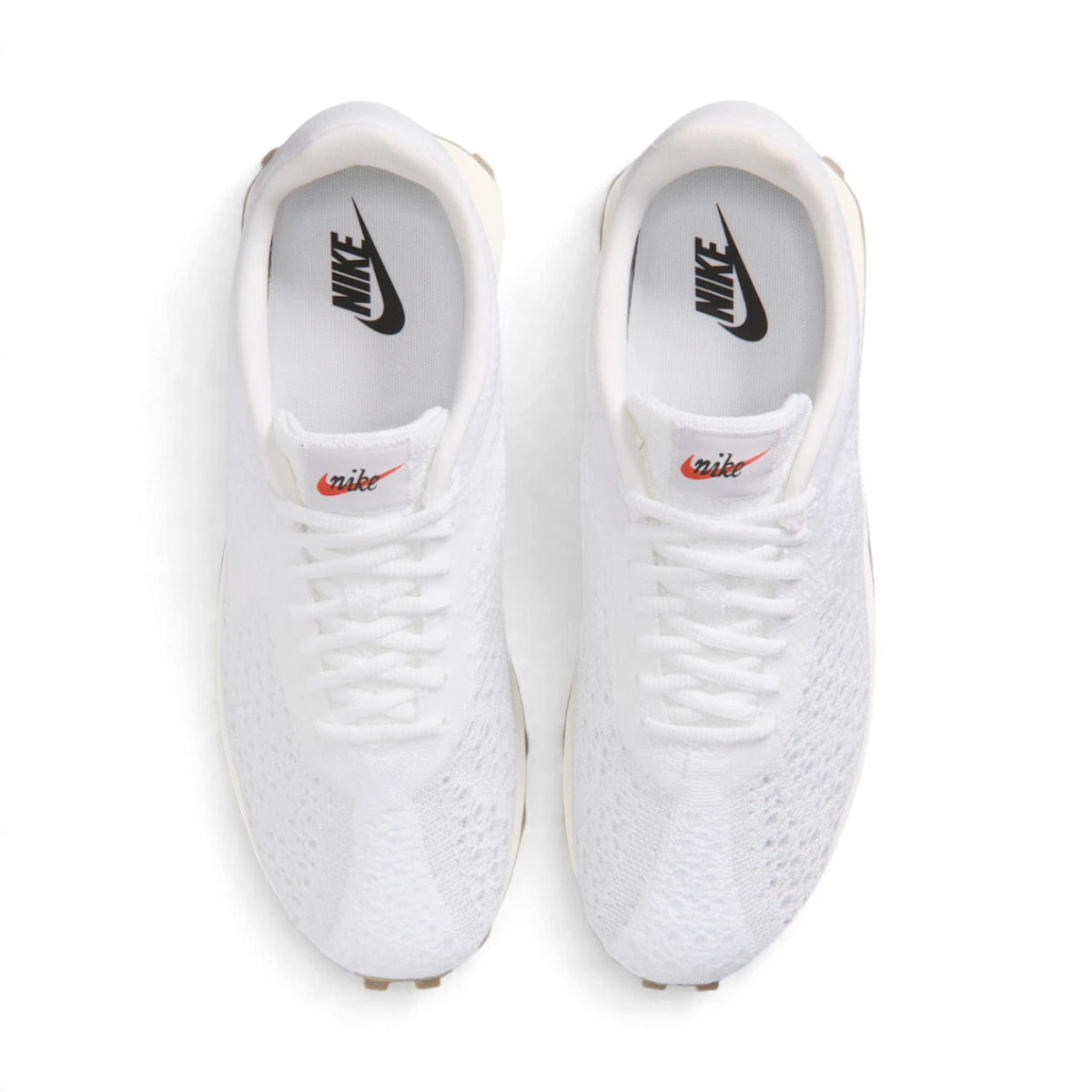 Overhead view of both sneakers showing the adaptive white knit forefeet, central lacing systems, and white insoles printed with black Nike branding.
