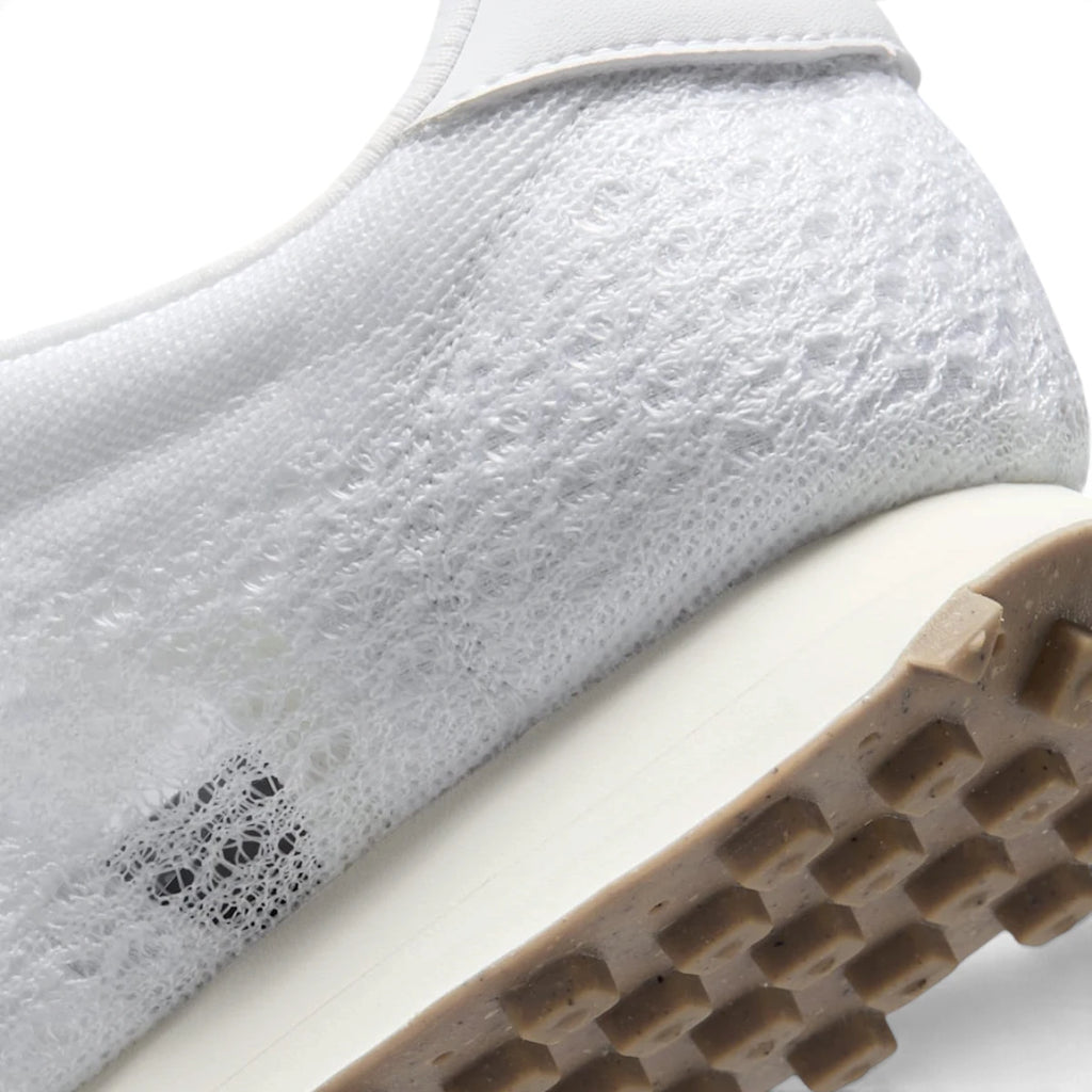 Close-up of the lateral heel transition, highlighting the smooth sail foam midsole, synthetic leather heel panel, and durable waffle tread pattern.