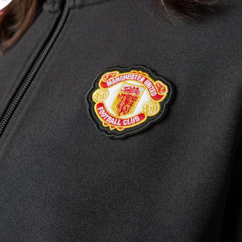 Macro close-up angle capturing the intricate embroidery, texture, and scalloped border of the vintage Manchester United football club badge.