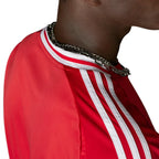 Macro close-up angle capturing the textured fabric weave, precision stitching of the embroidered Manchester United club badge, and the structured collar trim.