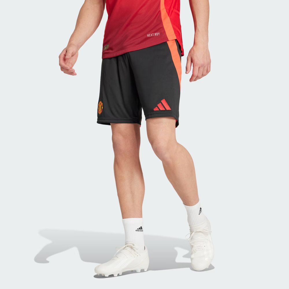 Person wearing black Adidas shorts with a red logo on a white background