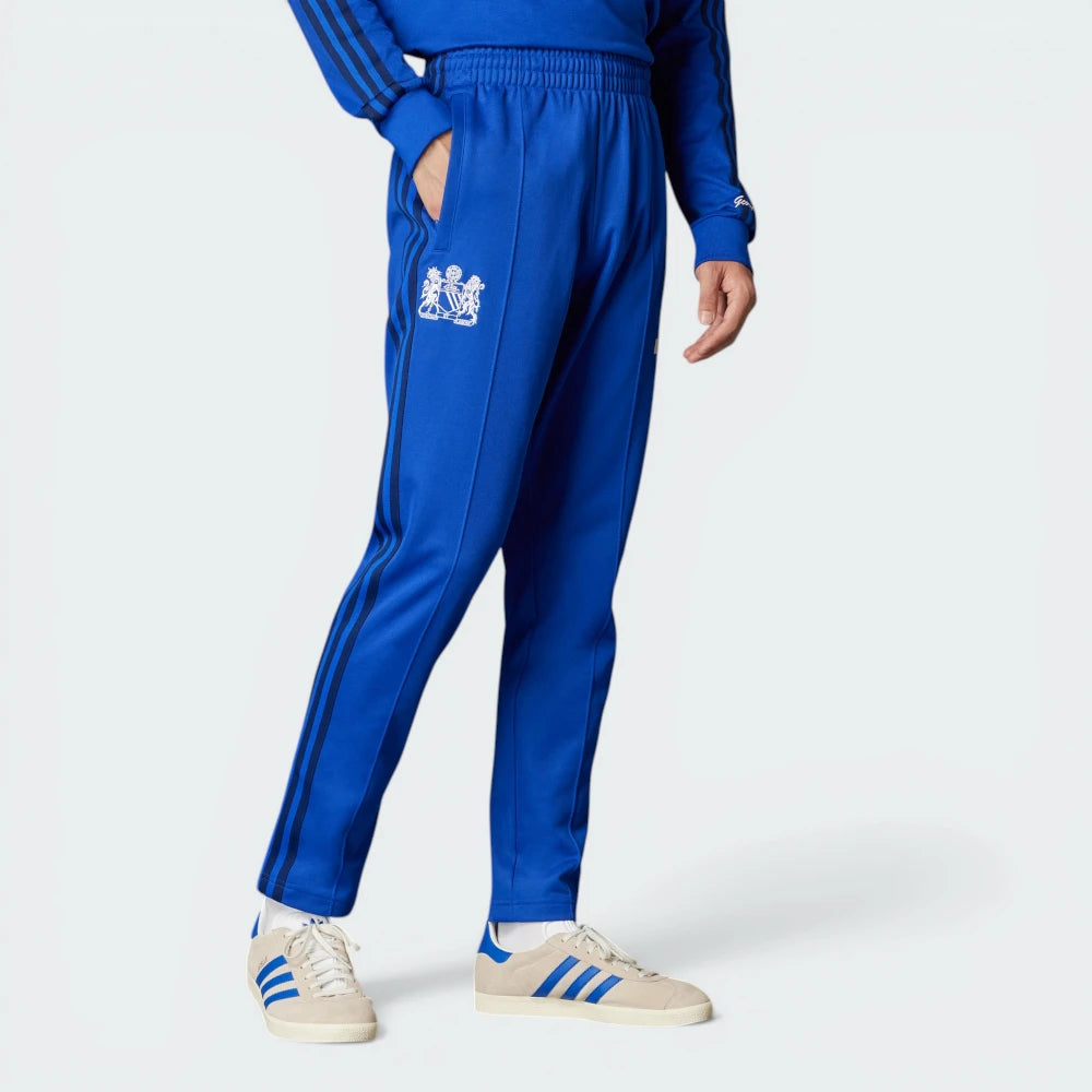 The Bold Blue track pants, highlighting the slim-cut leg and the vintage white Adidas 3-Stripes.