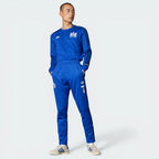 Person wearing a blue tracksuit with Adidas logo on a white background