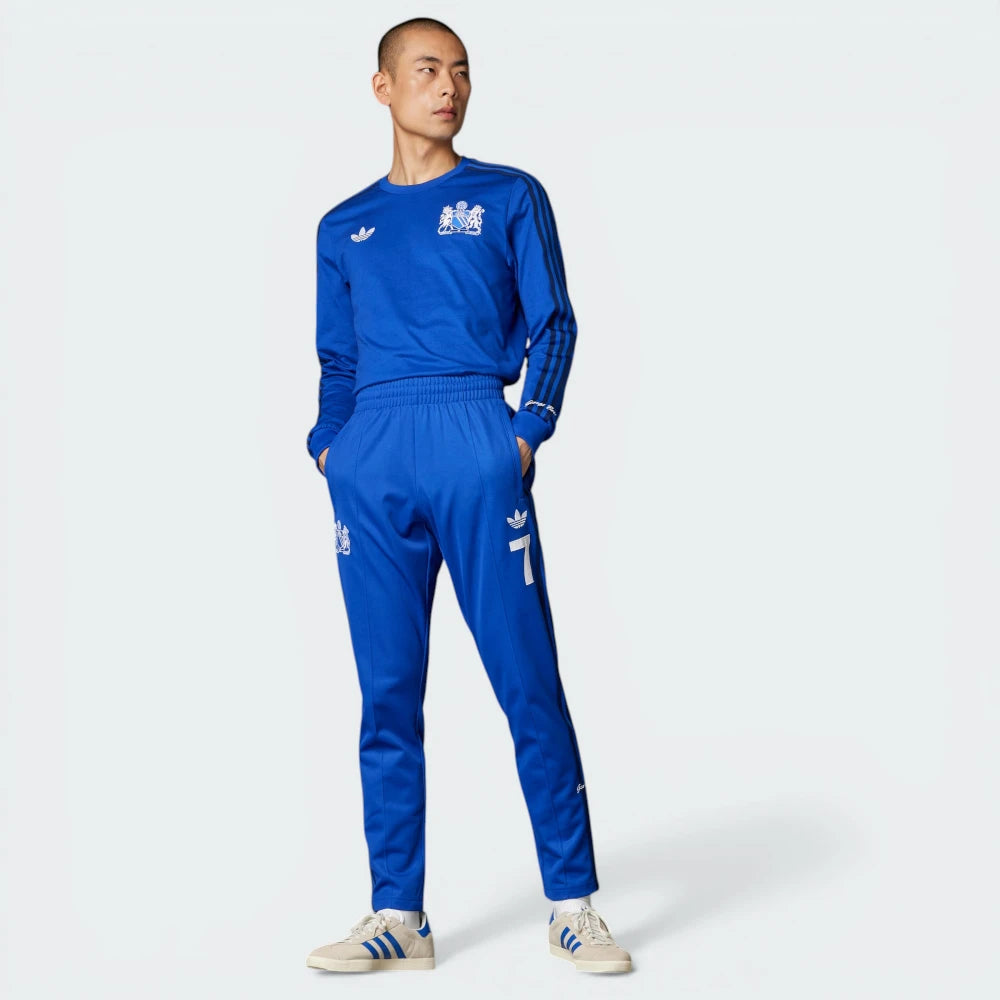 Person wearing a blue tracksuit with Adidas logo on a white background