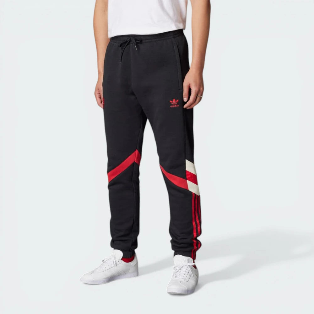 The Black track pants, highlighting the bold, oversized red 3-Stripes and the tapered leg.
