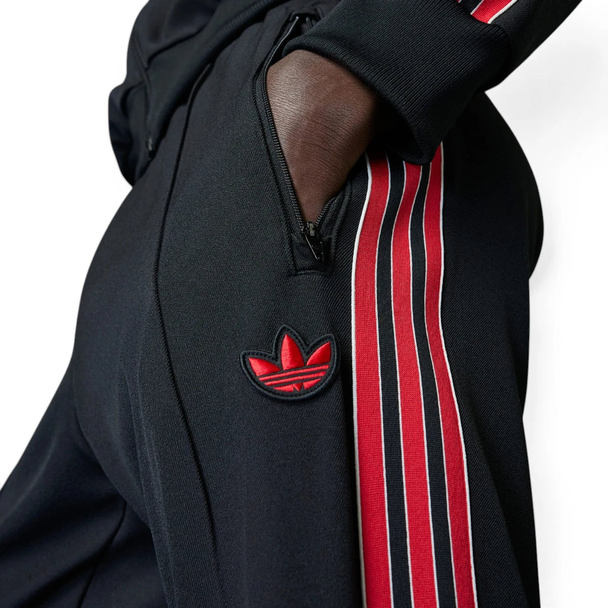 Detailed close-up angle capturing the secure front zipper pocket hardware and the embroidered red adidas Trefoil logo positioned neatly on the hip.