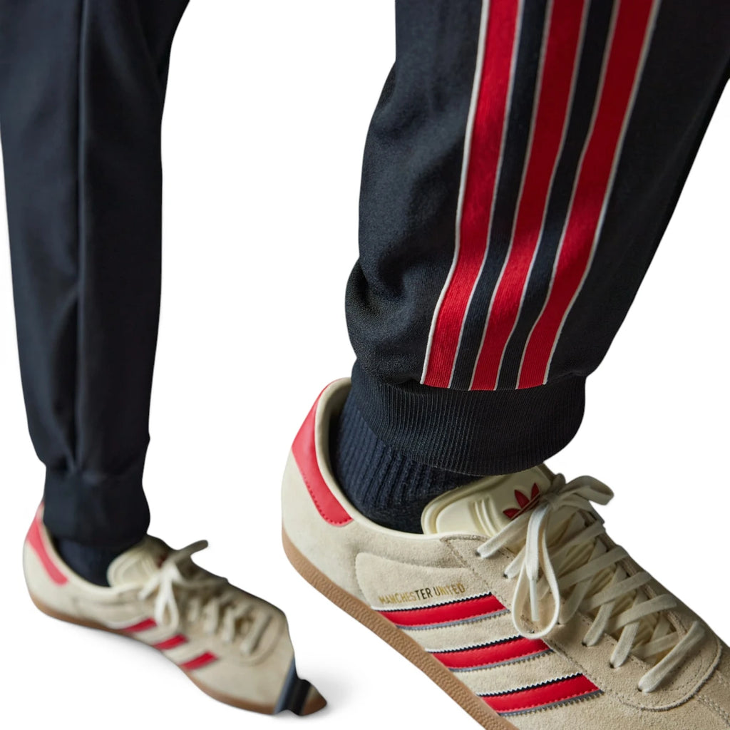 Close-up angle focusing on the ribbed ankle cuffs resting above vintage retro trainers, highlighting the multi-colour side tape termination.