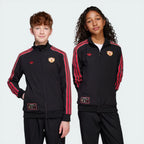 Two children wearing black tracksuits with red stripes and logos on a white background