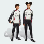 Side profile of the Kids' Man Utd Tiro 24 pants, highlighting the slim, tapered leg and the classic white 3-Stripes branding.
