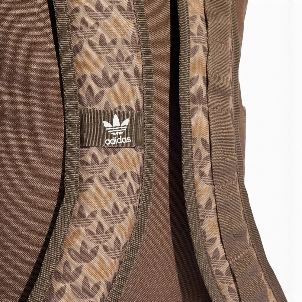 Highlights a close-up of the adjustable shoulder straps, showing the fabric weave texture, the integrated monogram graphics, and the stitched-on fabric tab featuring the classic white adidas Trefoil emblem.