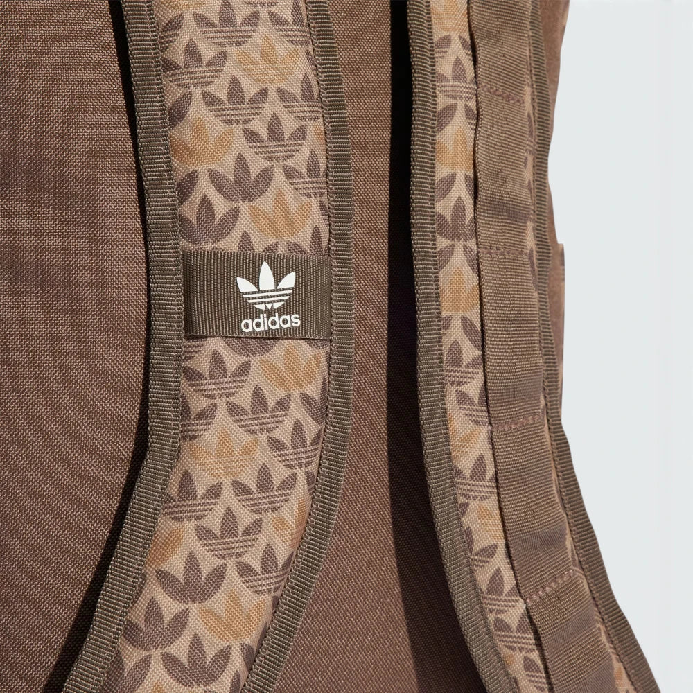 Highlights a close-up of the adjustable shoulder straps, showing the fabric weave texture, the integrated monogram graphics, and the stitched-on fabric tab featuring the classic white adidas Trefoil emblem.