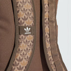 Highlights a close-up of the adjustable shoulder straps, showing the fabric weave texture, the integrated monogram graphics, and the stitched-on fabric tab featuring the classic white adidas Trefoil emblem.
