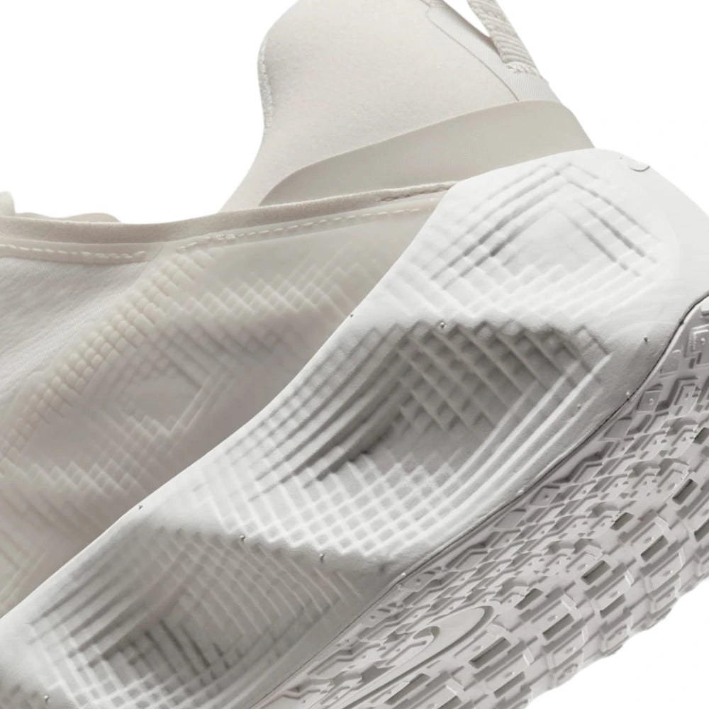 Close-up of the side and heel area of a white athletic shoe, showing textured foam construction and a patterned outsole.