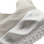 Close-up of the side and heel area of a white athletic shoe, showing textured foam construction and a patterned outsole.