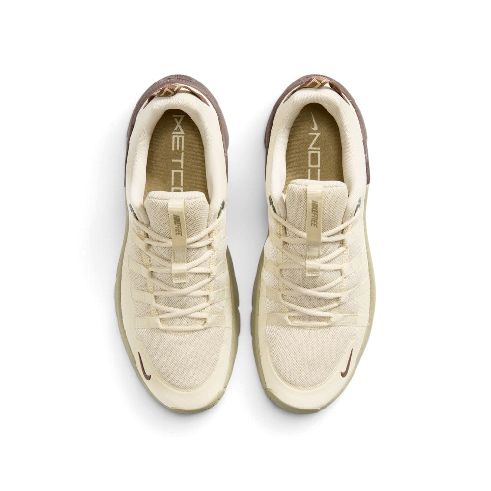 Direct overhead view of both shoes laid flat, showcasing the uniform khaki mesh toe box, the parallel webbed lace loops, the branded tongue tabs reading "NIKE FREE", and the printed Metcon insoles