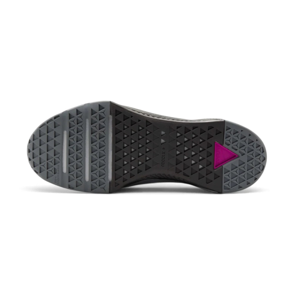Displays the full-length flat rubber sole, showcasing the triangular tread pod grid, horizontal forefoot flex grooves, central "reactx" midsole shank text, and the rear triangular cutout revealing the bright Vivid Purple Hyperlift plate.