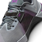 Details the micro-precision of the open-holed mesh upper, showing the reinforced dark toe guard with mini Swoosh, grey laces, black midfoot band with purple emblem, and the textured rubber sidewall wrap.