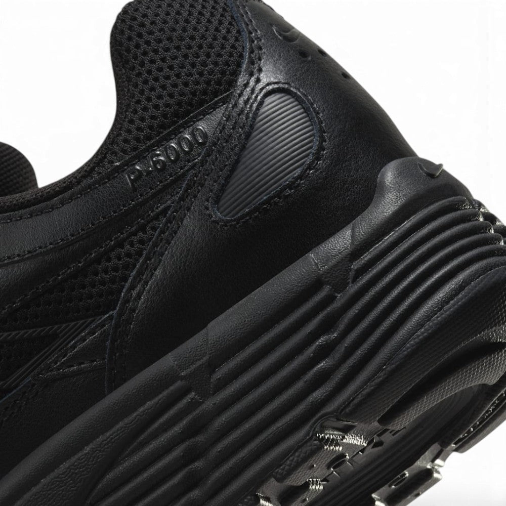 Highlights the "unreal" clean finish of the rear lateral quarter, displaying the debossed "P-6000" collar lettering, ribbed black foam midsole, and lugged rubber outsole tread.