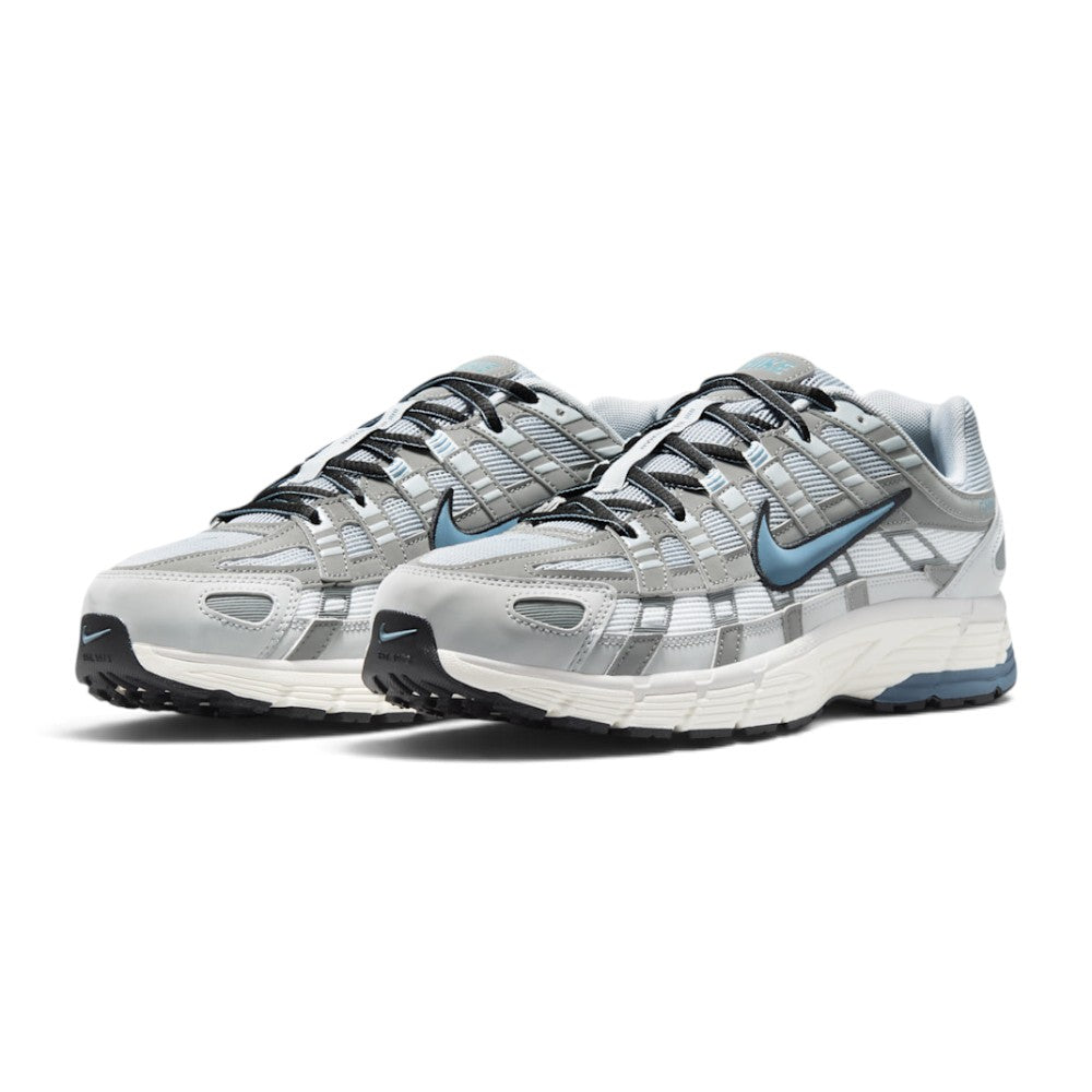 Emphasising the low-slung, technical stance of the trainers and the high-contrast harmony between the breathable white mesh base, metallic silver cage panels, and subtle blue accent hits.