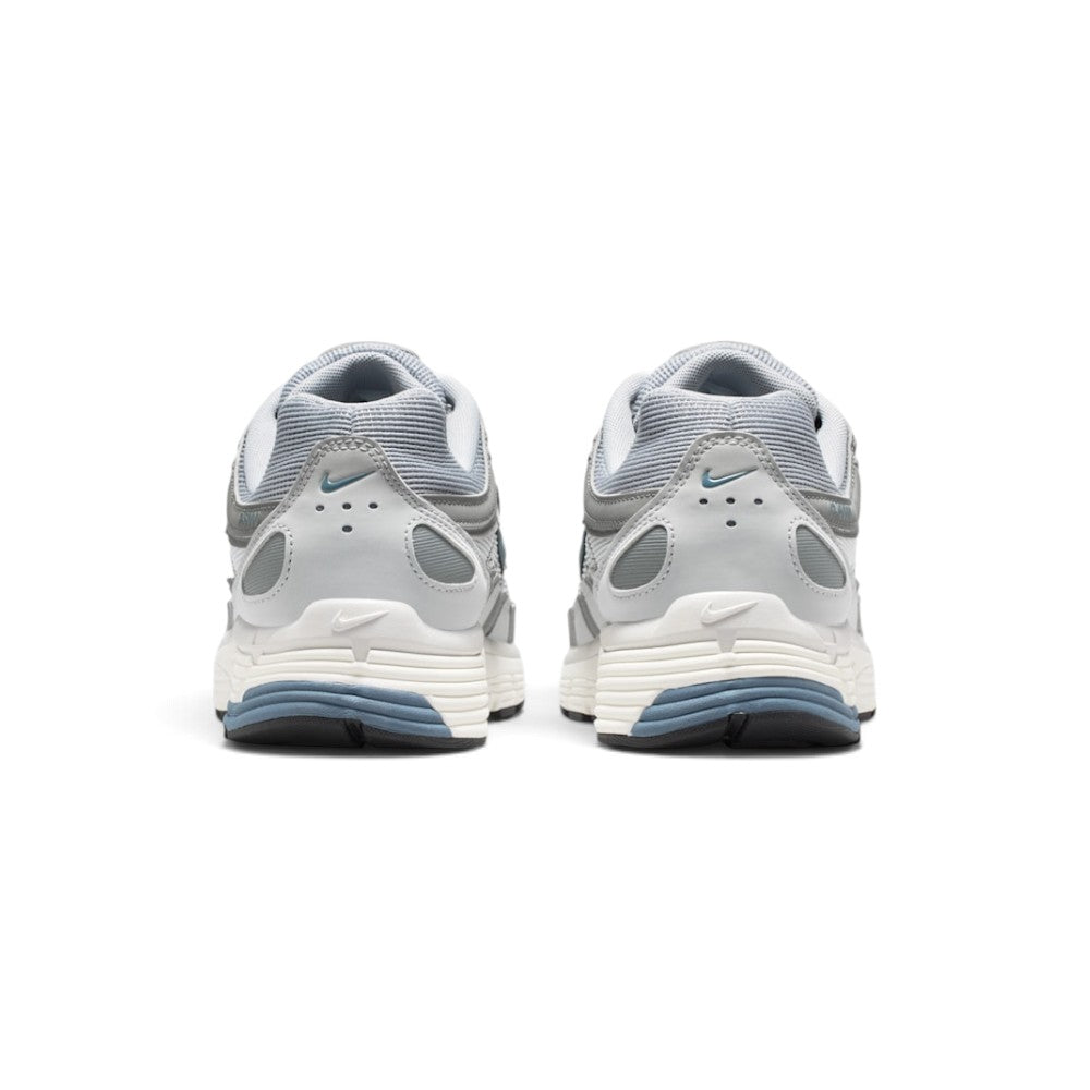 Focuses on the rear profile, displaying the structured grey synthetic heel counters, micro blue Swooshes, ventilation perforations, and the multi-layered Sail and blue foam midsole base.