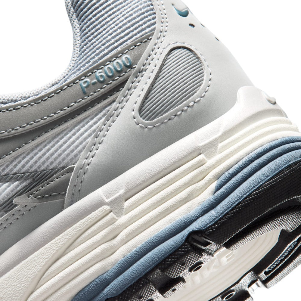 Highlights the "unreal" clean finish of the rear lateral quarter, displaying the embossed "P-6000" collar script, ribbed Sail foam midsole, slate blue wedge insert, and black lugged rubber outsole tread.